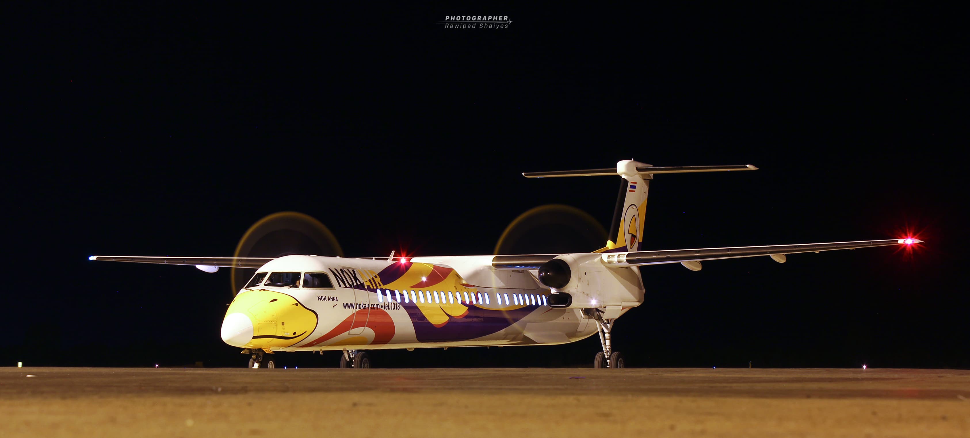 ညဘက် လေယာဉ်ရပ်နားရာ ကွင်းပေါ်ရှိ Nok Air De Havilland Canada Dash 8-400 တာဘိုပရော့ပ် လေယာဉ် HS-DQA
