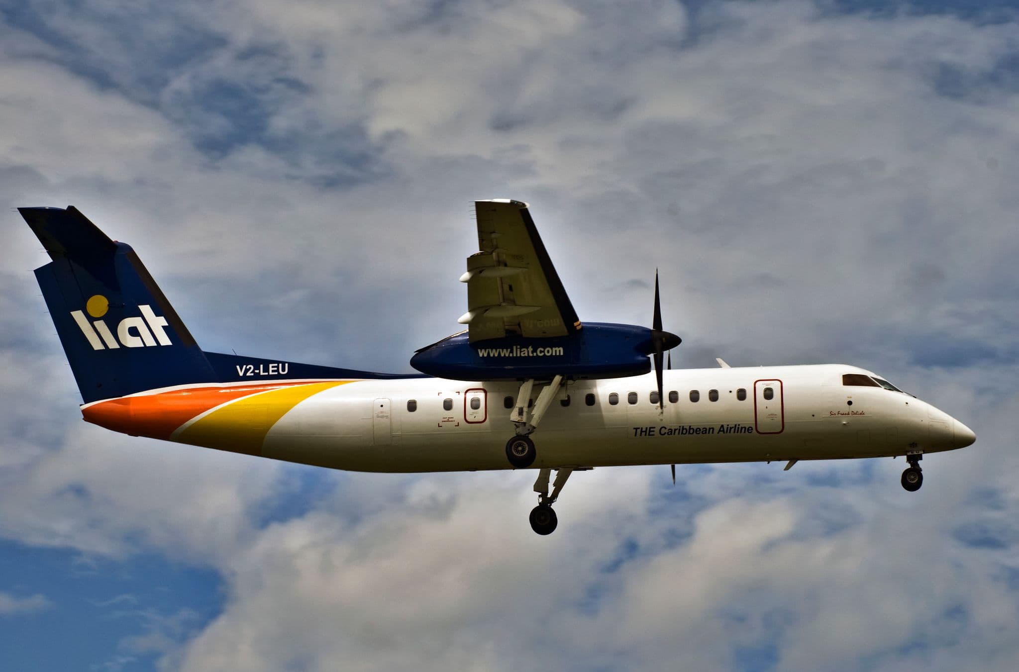 LIAT Dash 8 turboprop flying against a cloudy sky over Barbados