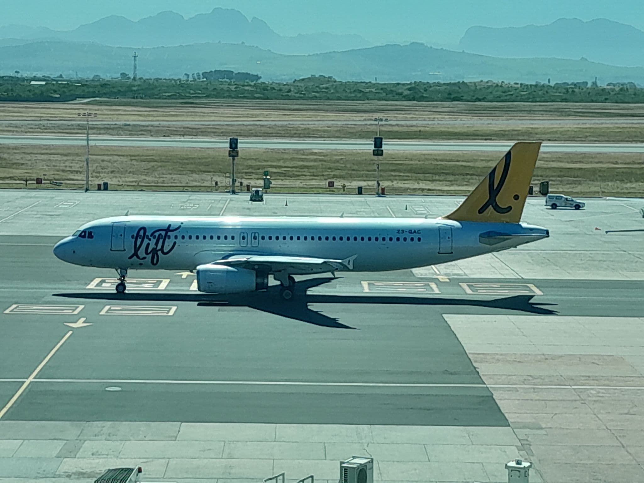 LIFT Airbus A320 ZS-GAC taxiing at Cape Town International Airport with mountains behind