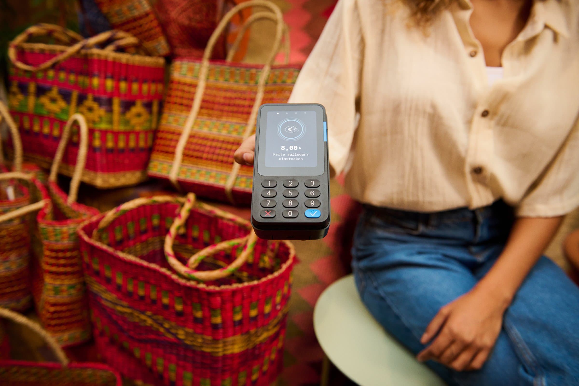 Card reader held out for contactless payment at a market stall selling woven bags