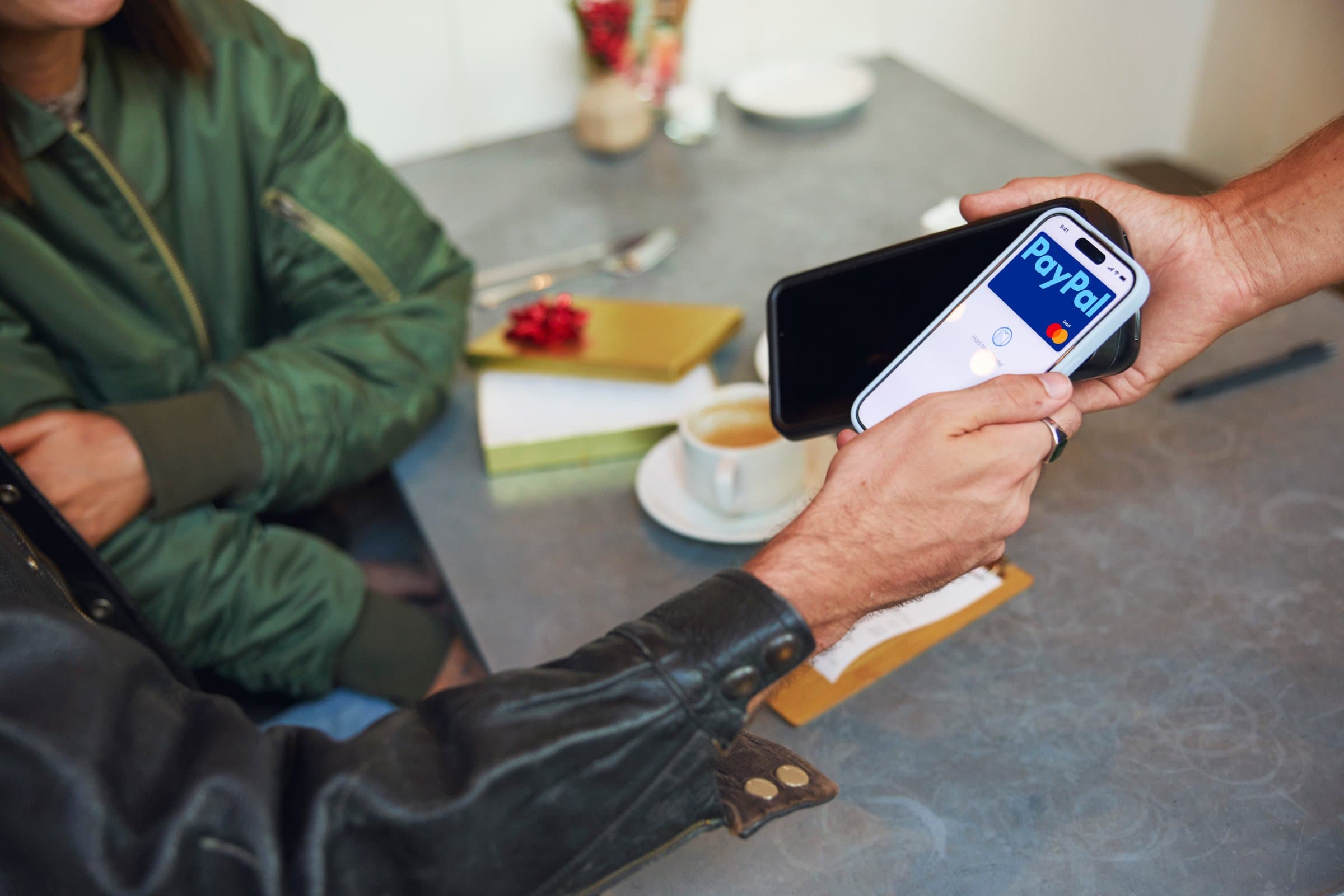 Customer paying in store by tapping a phone showing the PayPal card on a card reader