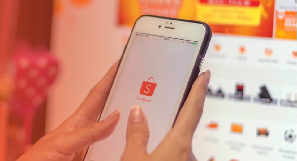 Hand holding a phone showing the Shopee app