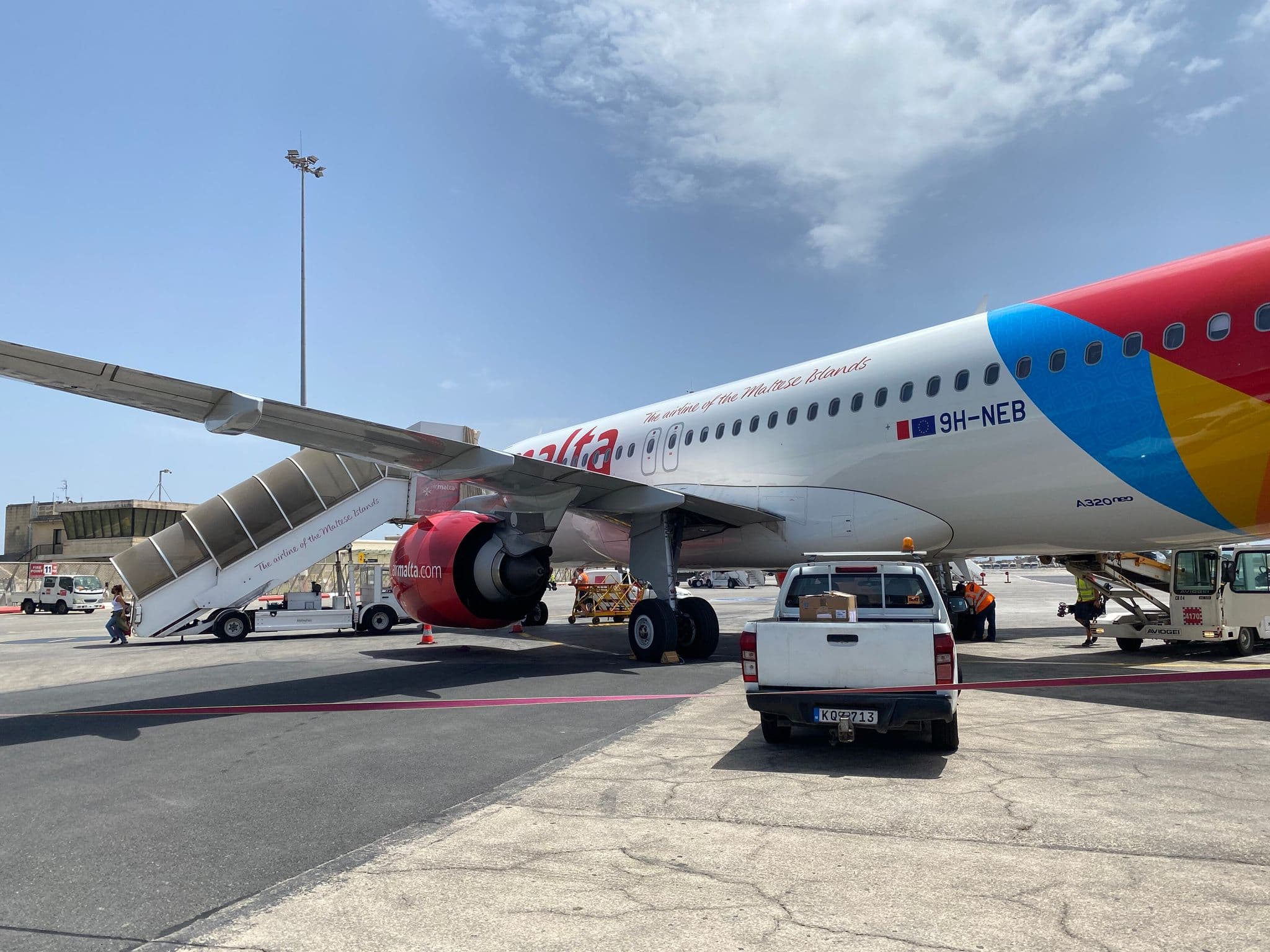 Air Malta Airbus A320neo on the apron with boarding stairs and ground vehicles