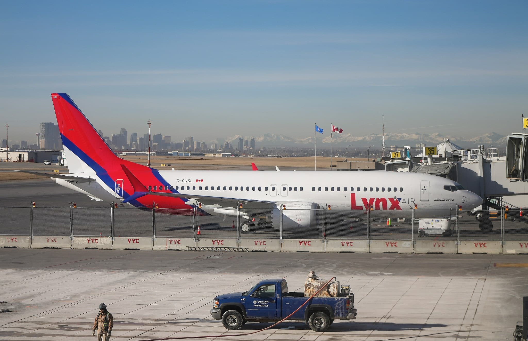 Lynx Air Boeing 737 MAX 8 parked at Calgary International Airport with the city skyline behind