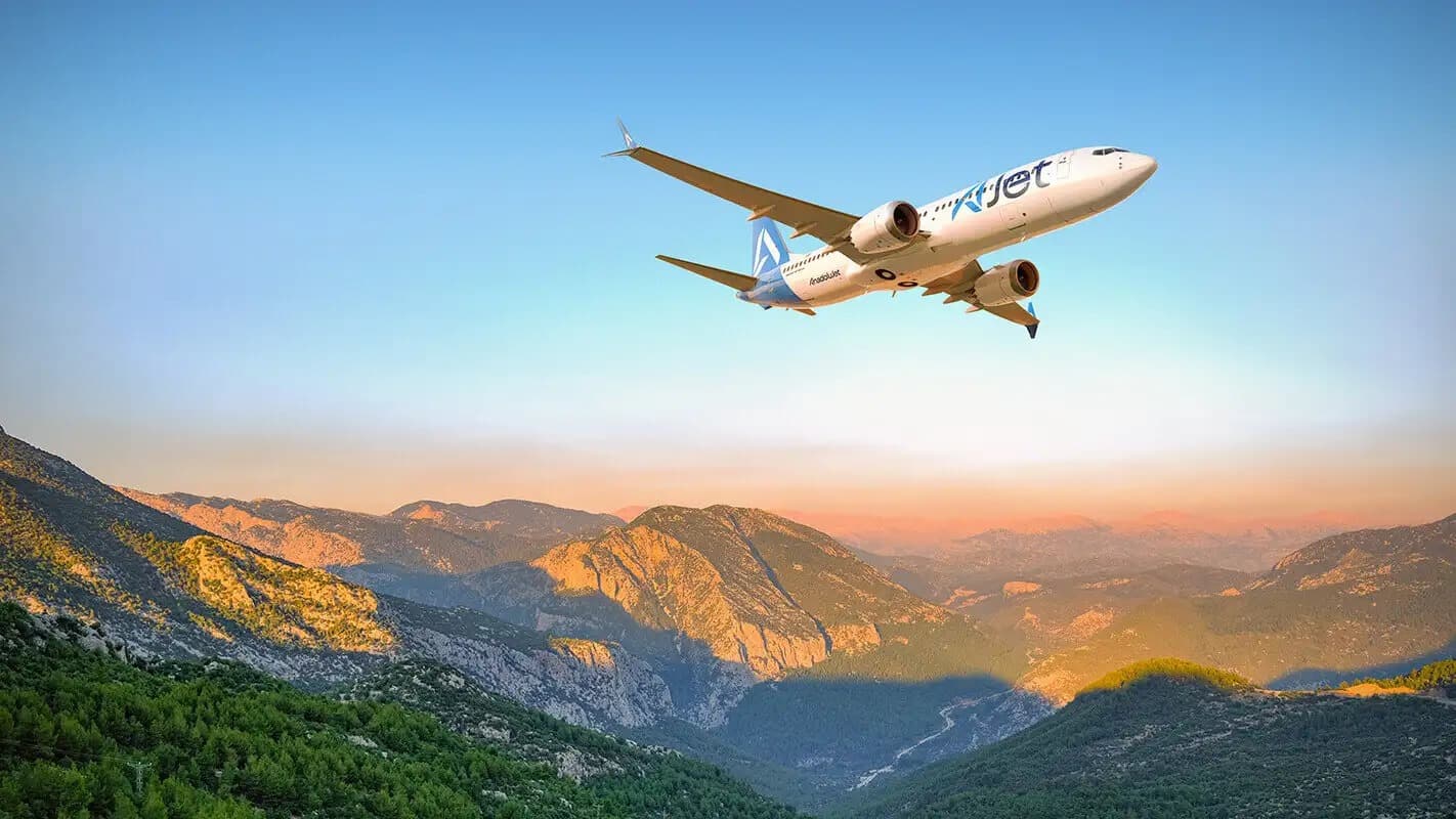 Boeing 737 da AJet em voo sobre montanhas ao pôr do sol