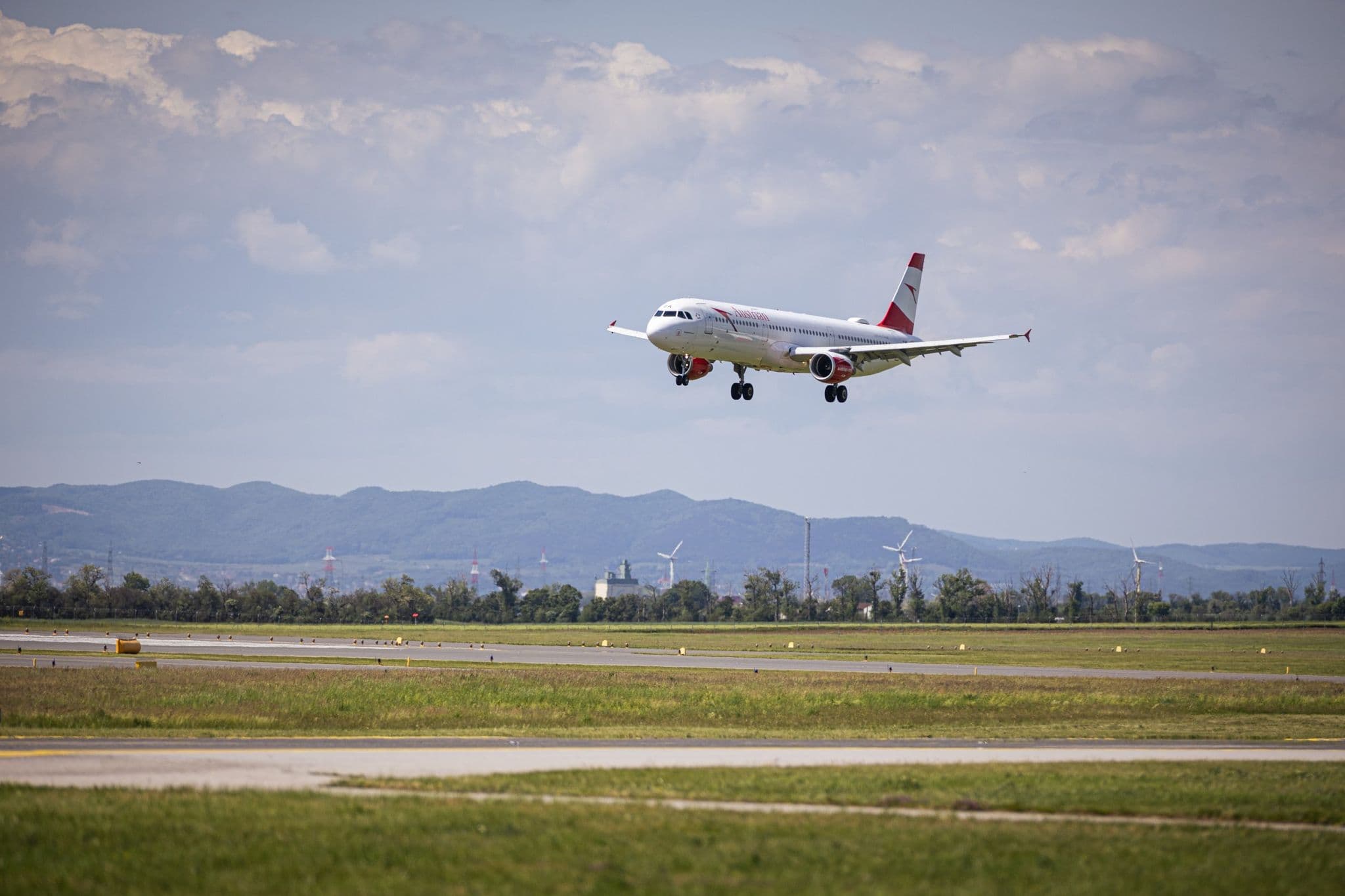 Austrian Airlines Airbus A320 系列客機進近降落,背景為山丘