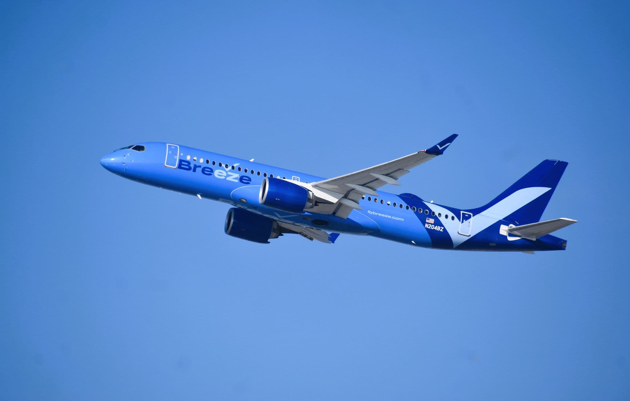 Airbus A220 da Breeze Airways em voo contra um céu azul, em Los Angeles